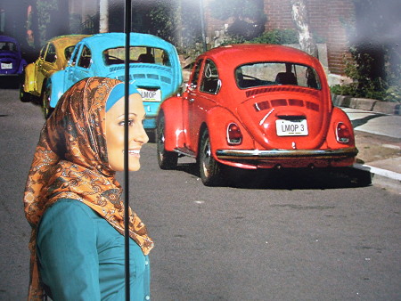 Close-up of photo of Rayyan from ‘Little Mosque’ crossing a street where three old Beetles are parked