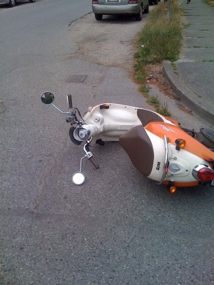Scooter laying on its side on street by curb