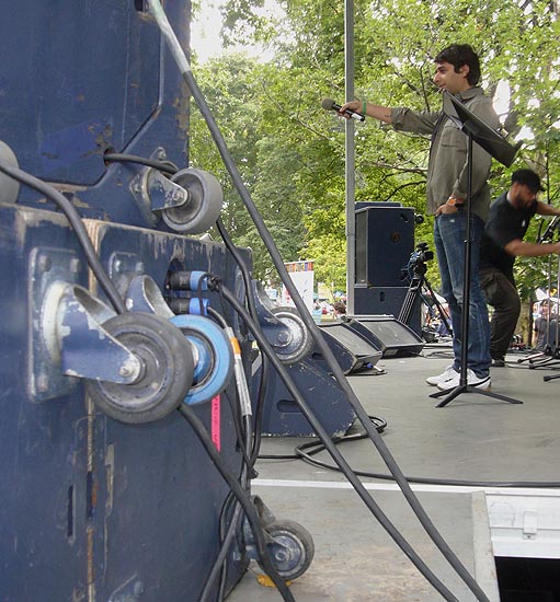 Jian Ghomeshi, hand and microphone outstretched, centre stage with roadie