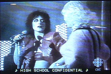 Carole Pope and bewigged transvestive: ♪ HIGH SCHOOL CONFIDENTIAL ♪